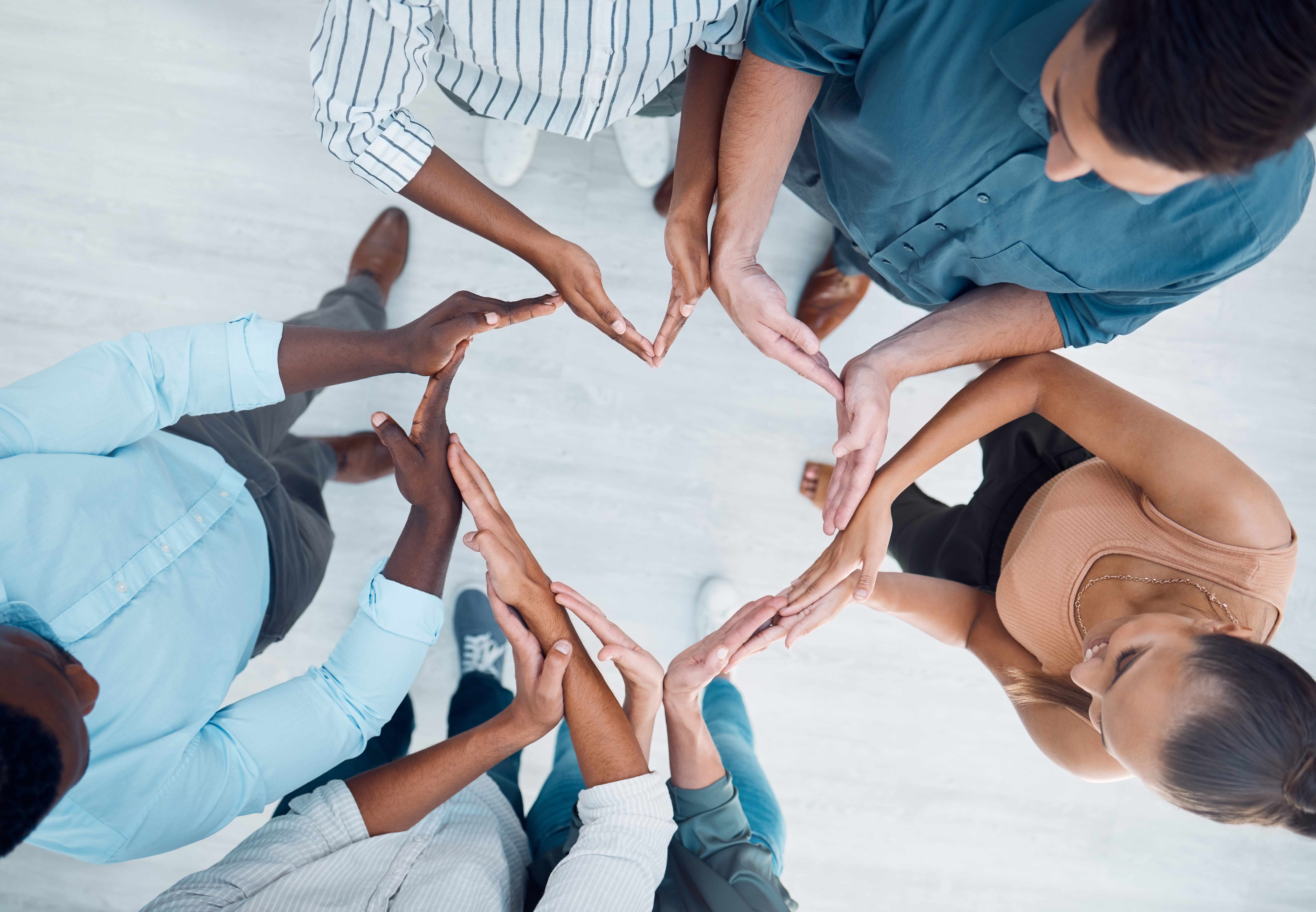 community in solidarity at the office. Group hand of employee workers in teamwork, collaboration and unity above in heart shape sign